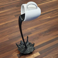 Sculpture de tasse volante avec liquide qui se renverse. Décoration en résine