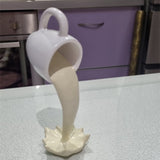 Sculpture de tasse volante avec liquide qui se renverse. Décoration en résine